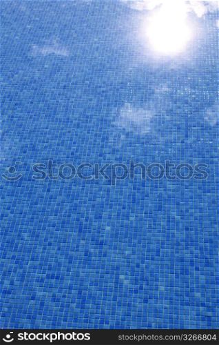 blue tiled swimming pool with sun reflexion summer vacation background
