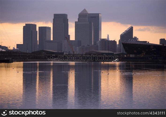 blue tone of canary wharf silhouette over canal at sunset