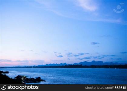 Blue tone sunset sky over Mae Khong river in Nakhon Phanom. Natural border between Thailand and Laos. Peaceful twilight scenery