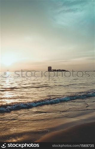 Blue toned beach with the silhouette of a building in the horizon