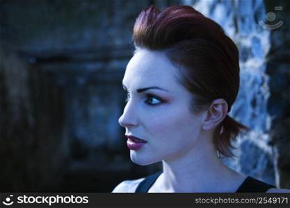 Blue-toned side view portrait of serious looking Caucasian woman.