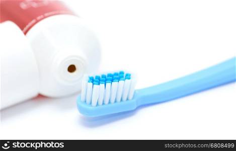 Blue toothbrush and tooth paste tube on white background. Closeup of the daily dental hygiene tool.
