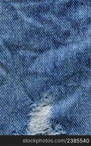 Blue torn grunge denim jeans texture. Jeans bit torn. Blue denim jean texture background. Jeans torn fabric texture