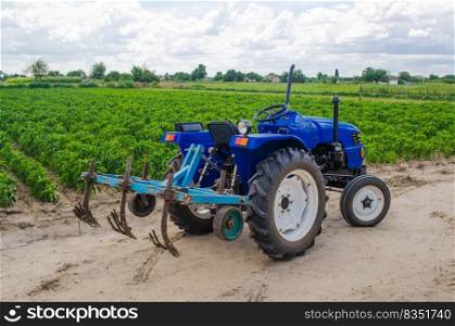 Blue tractor with a cultivator plow and the green field of the Bulgarian pepper plantation on the background. Farming, agriculture. Agricultural machinery and equipment, work on the farm. harvesting
