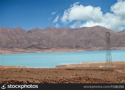 Blue water of a Moroccan reservoir against mountain and sky in rural Morocco.