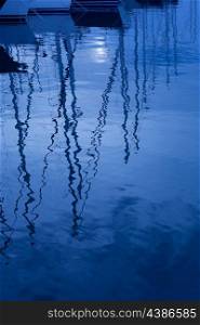 Blue water reflection of sailboats boats poles in waves tranquil water
