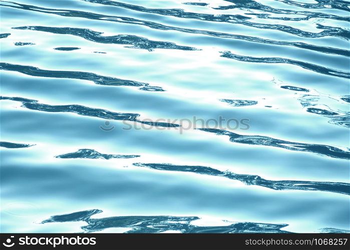 Blue water surface with waves and sun light reflections.
