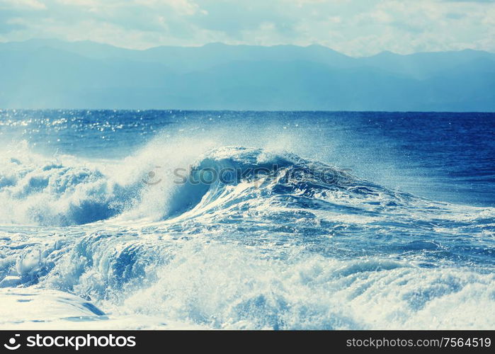 Blue wave on the beach. Blur background and sunlight spots. Dramatic natural background.