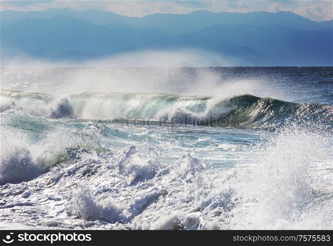 Blue wave on the beach. Blur background and sunlight spots. Dramatic natural background.
