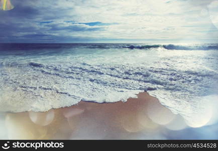 Blue wave on the beach. Blur background and sunlight spots. Peaceful natural background.