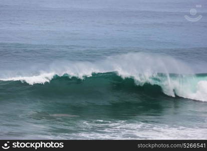 Blue wave on the beach. Blur background and sunlight spots. Peaceful natural background.