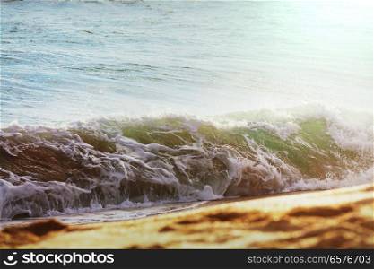Blue wave on the beach. Blur background and sunlight spots. Peaceful natural background.