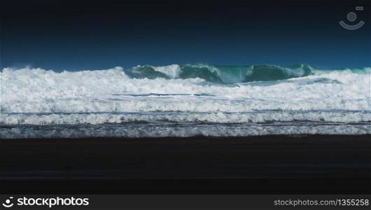 Blue waves crash down on beach in Cornwall, UK
