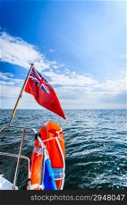 Blue wavy sea seascape. View from deck of yacht sailboat with british flag ensign and orange lifebuoy lifebelt. Safety travel. Yachting.