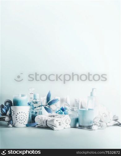 Blue white beauty setting for spa, wellness or skin care concept. Burning candles with beautiful flowers, towels with cosmetic products for full feeling and relaxing standing on table. Copy space