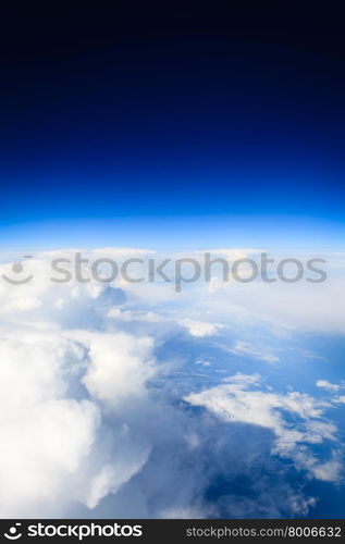 Blue white cloudy sky. View from window of airplane flying in clouds. Skyscape cloudscape. Bird&#39;s eye.