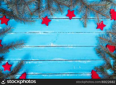 blue wooden background of parallel boards with green spruce branches and Christmas decor, empty space in the middle
