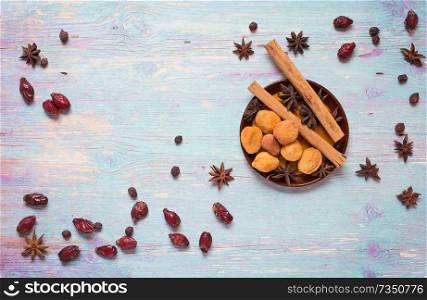 blue wooden background with cinnamon, anise, dog rose  and dried apricots