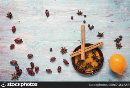 blue wooden background with cinnamon, anise, dog rose  and lemon