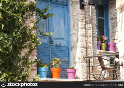 Blue wooden door and colorful flowerpots of stone house