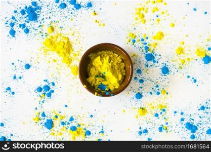 blue yellow color powder around bowl white backdrop