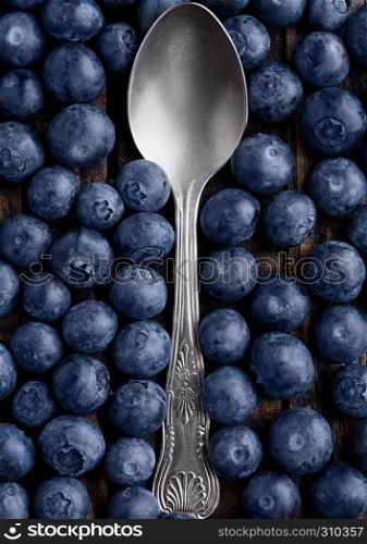 Blueberries around spoon close up photo. Natural healthy food. Still life photography