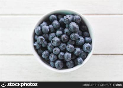 Blueberries fruit in bowl on the wooden table background , top view