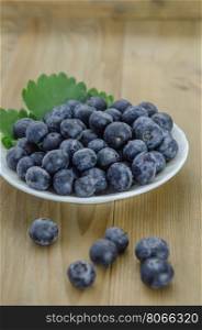 Blueberries in a bowl. Blueberries on white plate over wooden background