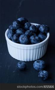 Blueberries in a bowl on a wood background