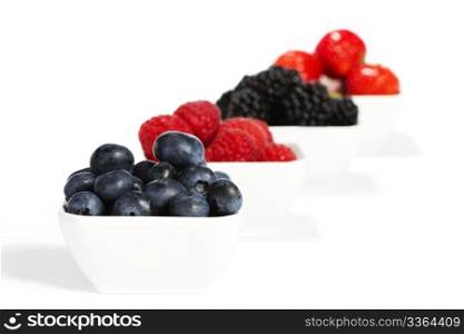 blueberries in a bowl with other berries in background. blueberries in a bowl with other wild berries in background on white background