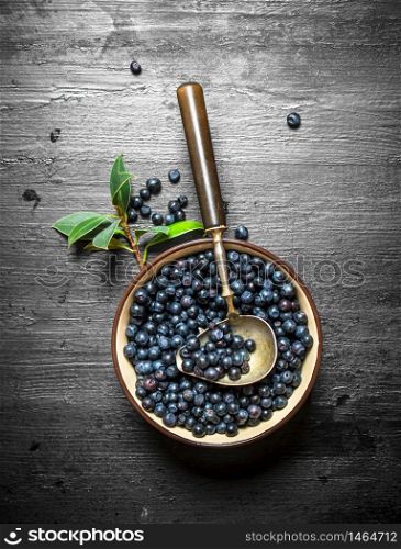 Blueberries in a Cup with a spoon. On a black wooden background.. Blueberries in cup with a spoon.