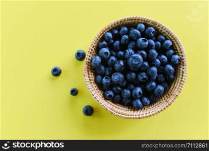 Blueberries in basket on yellow background , top view