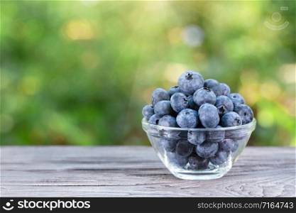 Blueberries in glass bowl on wooden table. Summer still life. Blueberries in glass bowl on wooden table