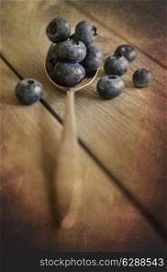 Blueberries in rustic setting with old wooden background with added texture filter