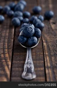 Blueberries on old spoon on grunge wooden board. Natural healthy food. Still life photography