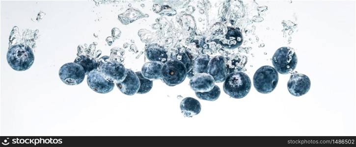 Blueberries sinking into water with air bubbles on white background. Photo for banner. Berries background. Blueberries sinking into water with air bubbles on white background.