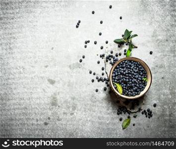 Blueberries with leaves in a Cup. On the stone table.. Blueberries with leaves in a Cup. On stone table.