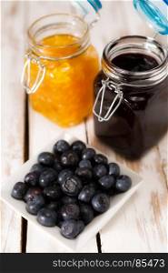Blueberries with orange and blueberry jam over a wooden table. Blueberries over a wooden table