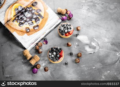 Blueberry and strawberry shortcake. There are hazelnuts, roses and wine corks on the table. Stone gray background.. Blueberry and strawberry shortcake. There are hazelnuts, roses and wine corks on the table. Stone background.