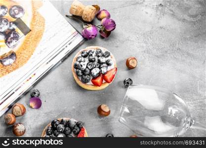 Blueberry and strawberry shortcake. There are hazelnuts, roses and wine corks on the table. Stone gray background.. Blueberry and strawberry shortcake. There are hazelnuts, roses and wine corks on the table. Stone background.