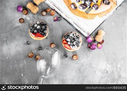 Blueberry and strawberry shortcake. There are hazelnuts, roses and wine corks on the table. Stone gray background.. Blueberry and strawberry shortcake. There are hazelnuts, roses and wine corks on the table. Stone background.