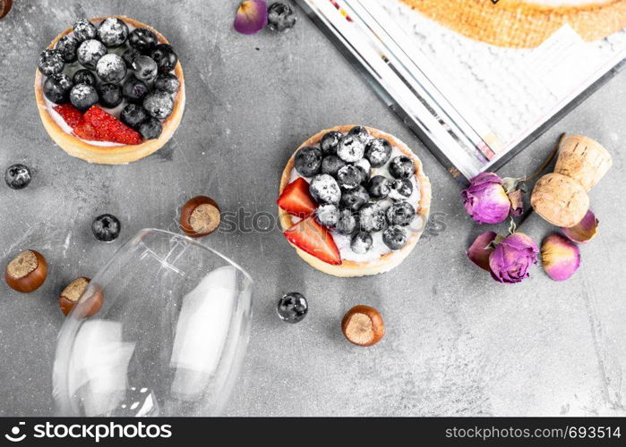 Blueberry and strawberry shortcake. There are hazelnuts, roses and wine corks on the table. Stone gray background.. Blueberry and strawberry shortcake. There are hazelnuts, roses and wine corks on the table. Stone background.