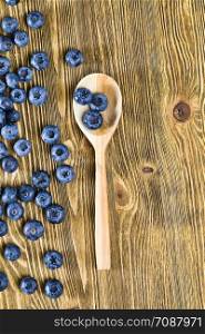 Blueberry berries on a table, summertime, photo of ripe and tasty berries scattered on a wooden table, close-up with a rustic wooden spoon. Blueberry berries on a table