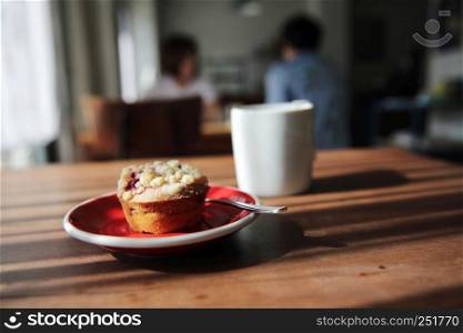 Blueberry muffin with hot tea on wood background