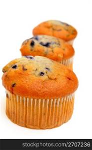 Blueberry muffins lined up in a row on a light colored background. Three Muffins
