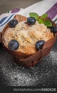 Blueberry muffins with powdered sugar and fresh berries.
