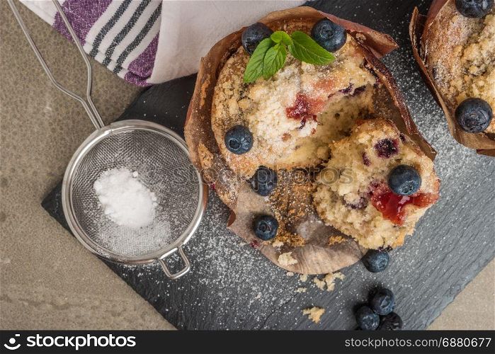 Blueberry muffins with powdered sugar and fresh berries.