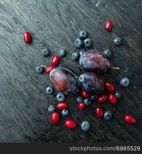 Blueberry, plum and dogwood on a dark wooden table. Blueberry, plum and dogwood