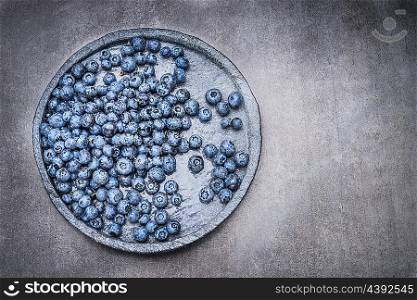 Blueberry with water drops on stone plate on gray background, top view, place for text