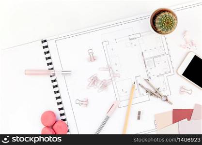 Blueprint flat project plan and office supplies on decorator table workspace. Swatches, tools, smartphone device and equipment background with copy space. Creative flat lay overhead top view concept
